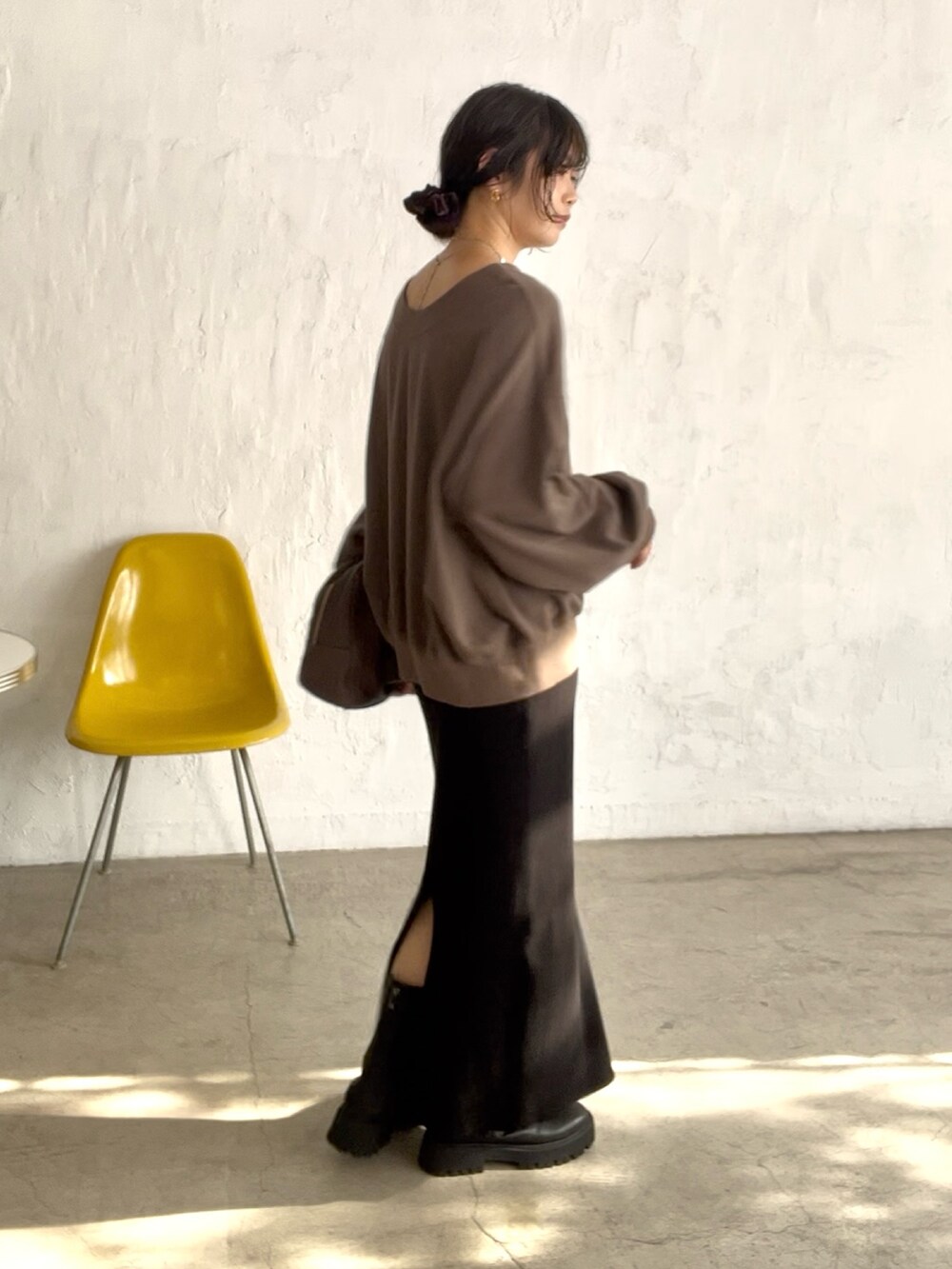 ブラック系のスカート、ブラック系のブーツ、ブラウン系のボストンバッグを着用したレディースの秋コーディネートの2枚目の写真