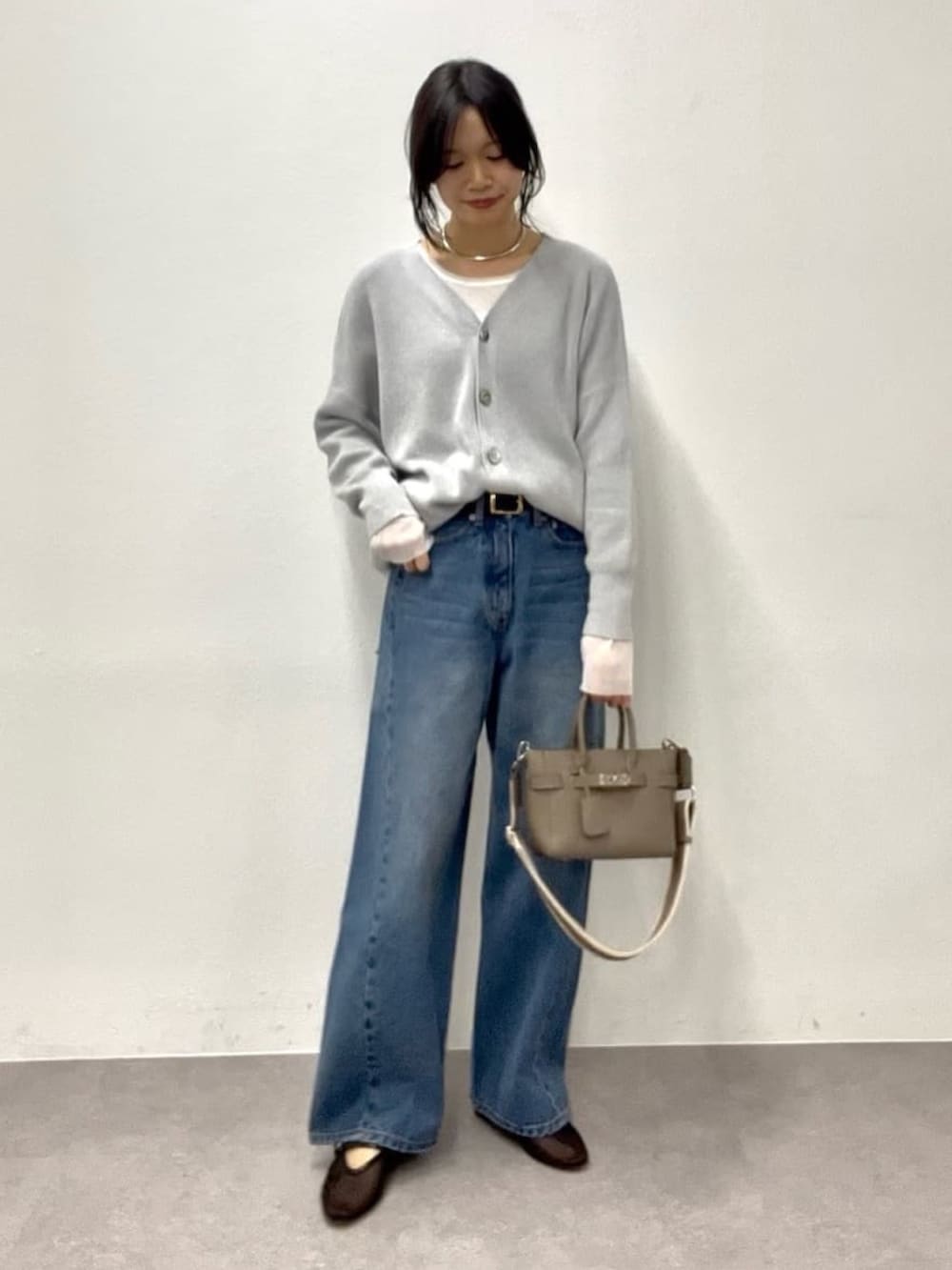 ホワイト系のTシャツ/カットソー、グレー系のニット/セーター、グレー系のトートバッグを着用したレディースの冬コーディネートの2枚目の写真