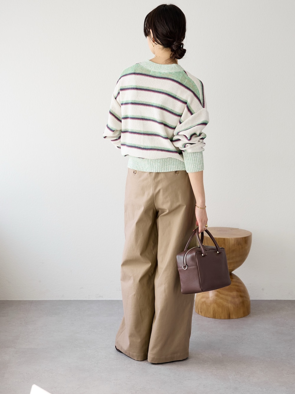 ベージュ系のチノパンツ、ブラウン系のボストンバッグ、ホワイト系のキャミソールを着用したレディースの冬コーディネートの4枚目の写真