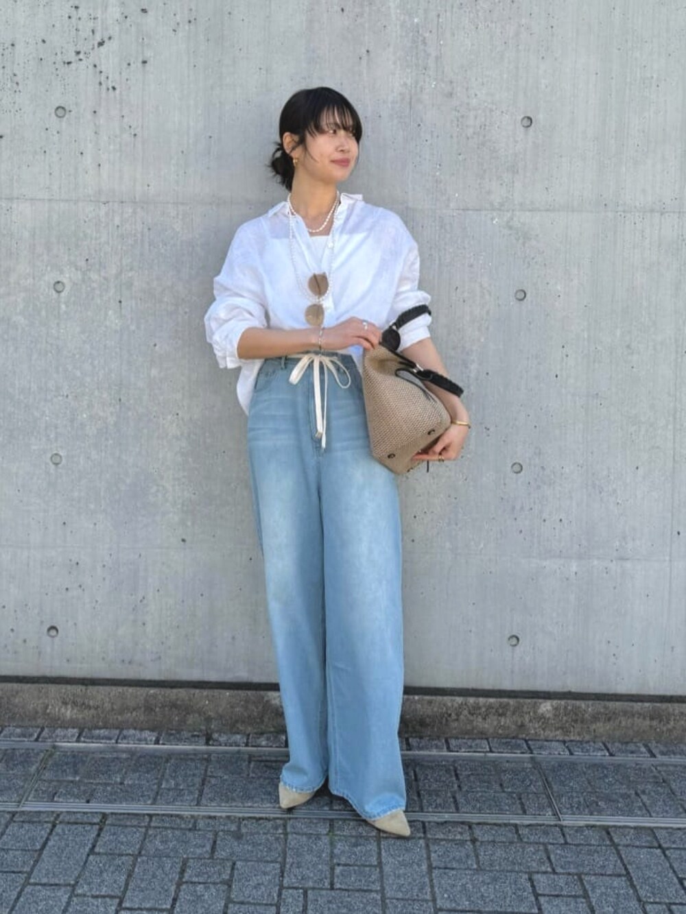 ブルー系のデニムパンツ、ベージュ系のパンプス、ブラック系のトートバッグを着用したレディースの夏コーディネートの2枚目の写真