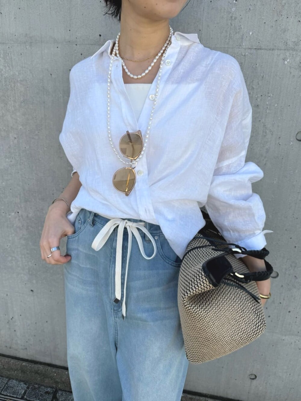 ブルー系のデニムパンツ、ベージュ系のパンプス、ブラック系のトートバッグを着用したレディースの夏コーディネートの5枚目の写真