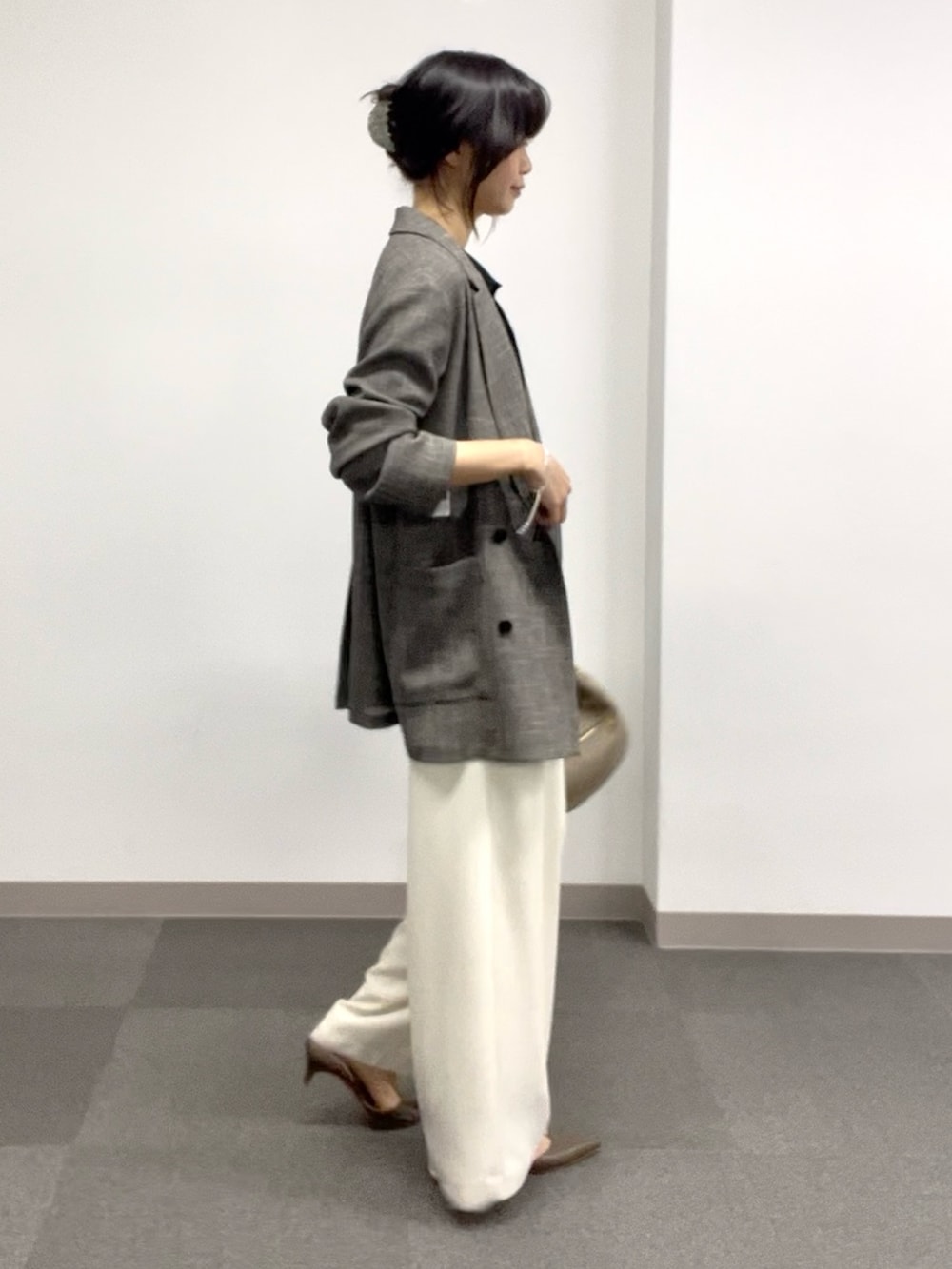 ブラック系のニット/セーター、ホワイト系のスラックス、グレー系のその他シューズを着用したレディースの春コーディネートの2枚目の写真