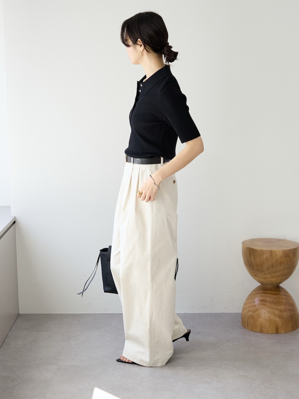 ホワイト系のチノパンツ、ブラック系のニット/セーター、ブラック系のトートバッグを着用したレディースの冬コーディネートの3枚目の写真