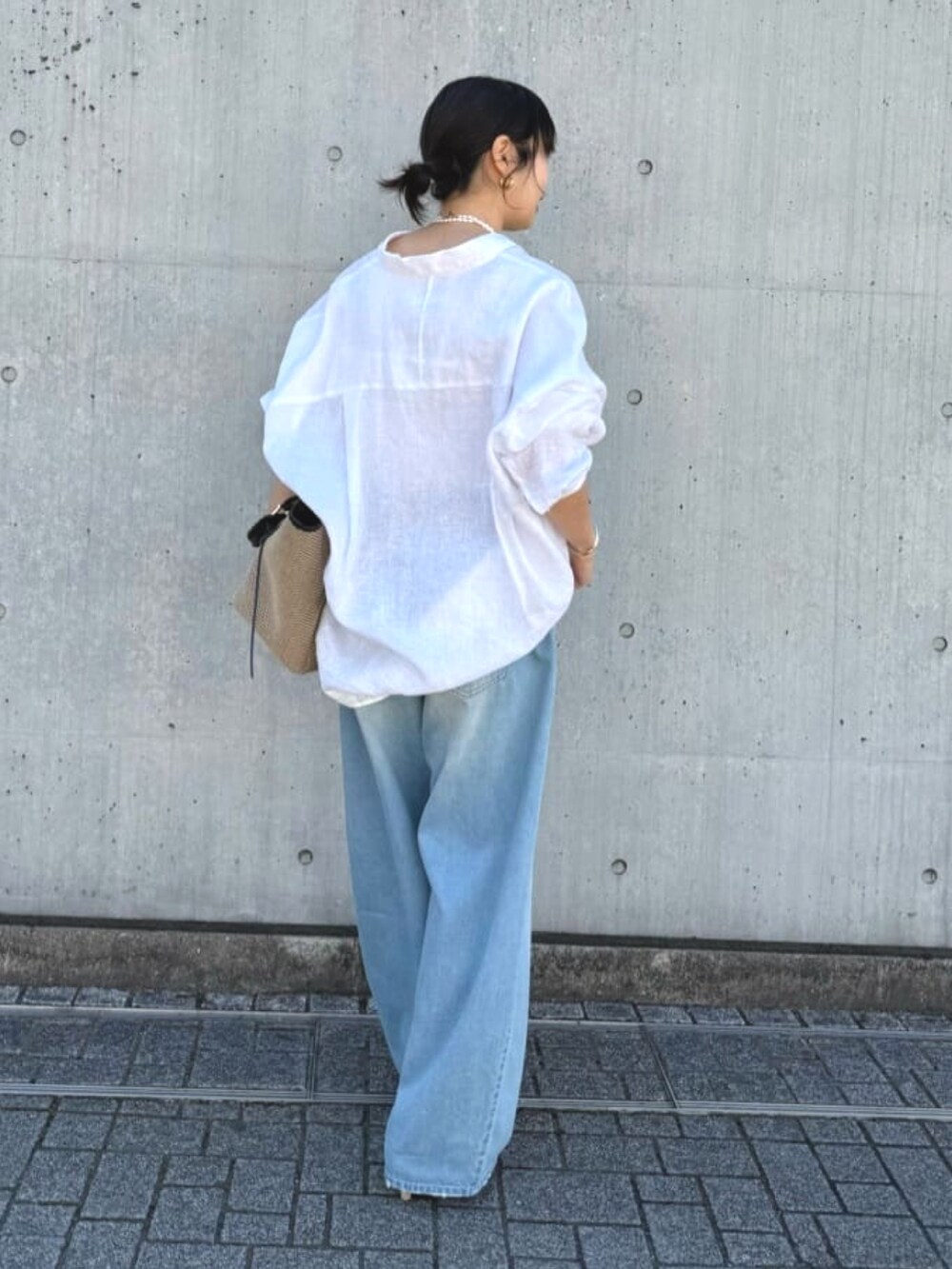 ブルー系のデニムパンツ、ベージュ系のパンプス、ブラック系のトートバッグを着用したレディースの夏コーディネートの4枚目の写真