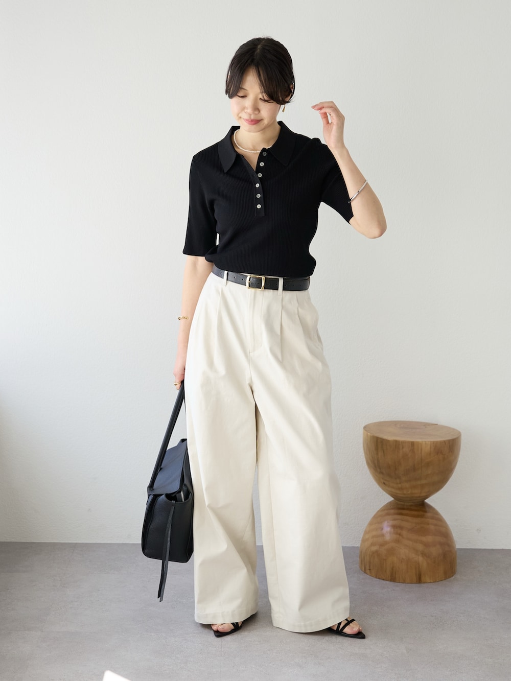 ホワイト系のチノパンツ、ブラック系のニット/セーター、ブラック系のトートバッグを着用したレディースの冬コーディネートの2枚目の写真