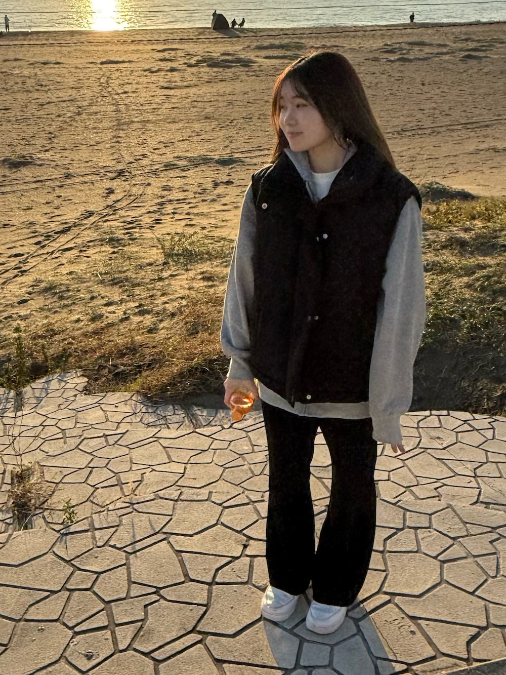 グレー系のパーカー、ブラック系のダウンベスト、ブラック系のその他パンツを着用したレディースの春コーディネートの3枚目の写真