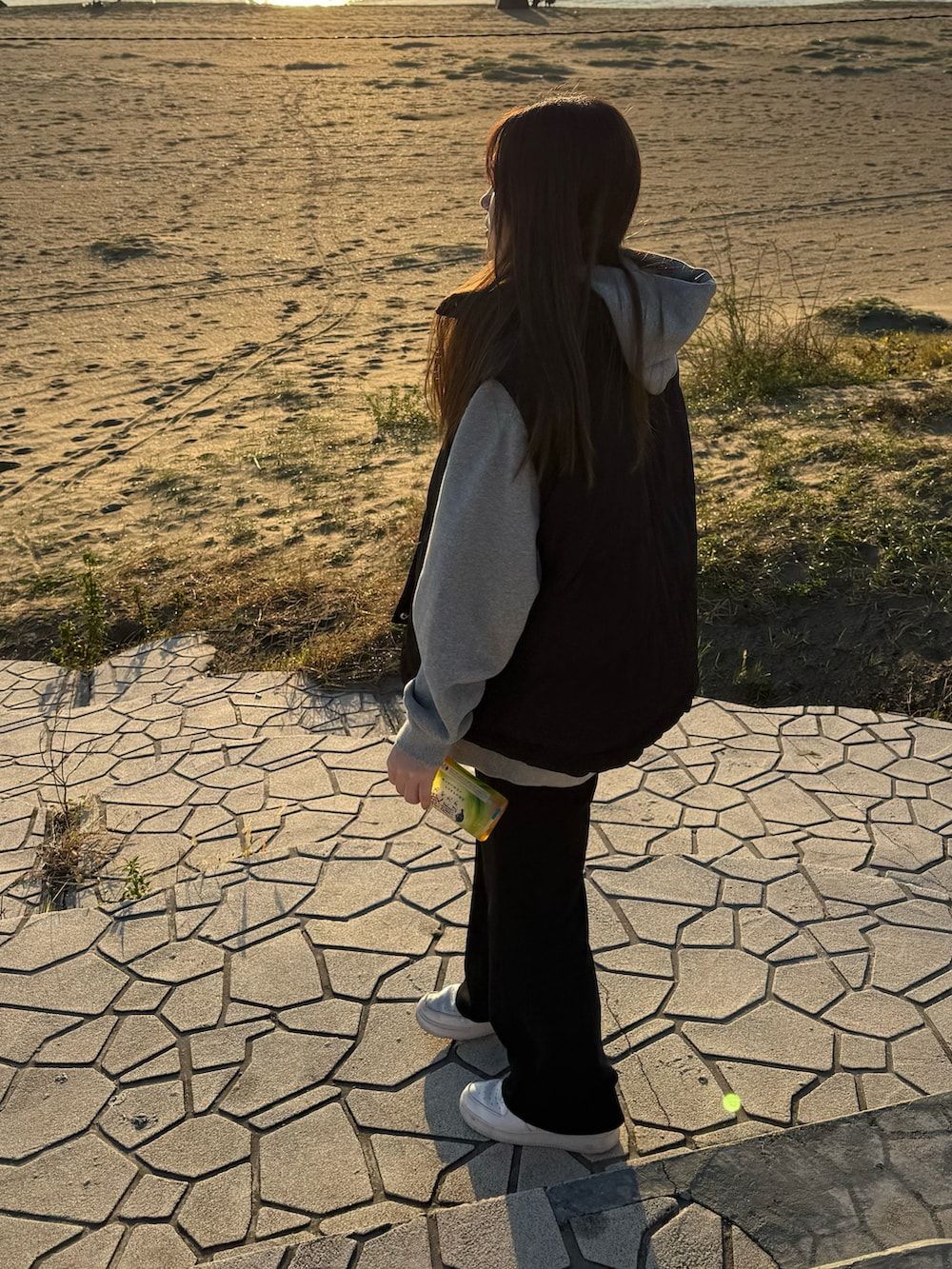 グレー系のパーカー、ブラック系のダウンベスト、ブラック系のその他パンツを着用したレディースの春コーディネートの2枚目の写真