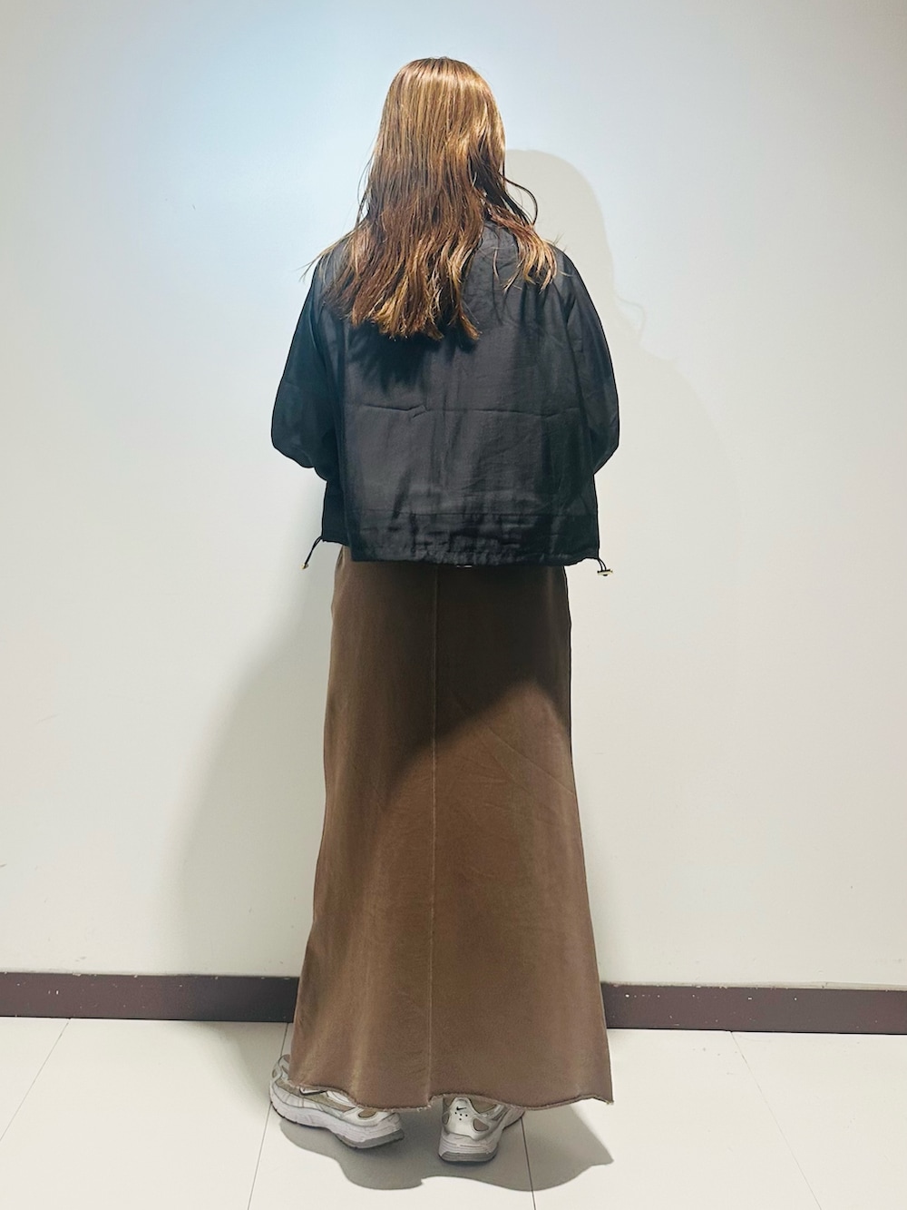 ブラック系のハンドバッグ、ブラウン系のスカート、ホワイト系のTシャツ/カットソーを着用したレディースの秋コーディネートの4枚目の写真