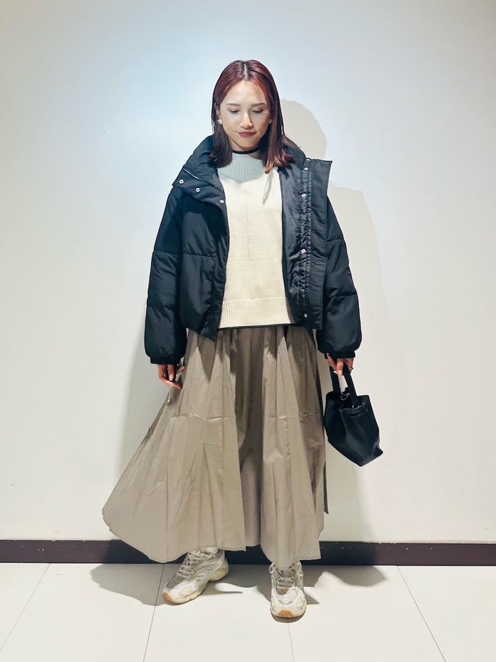 ブラック系のショルダーバッグ、ホワイト系のニット/セーター、グレー系のスカートを着用したレディースの秋コーディネートの2枚目の写真