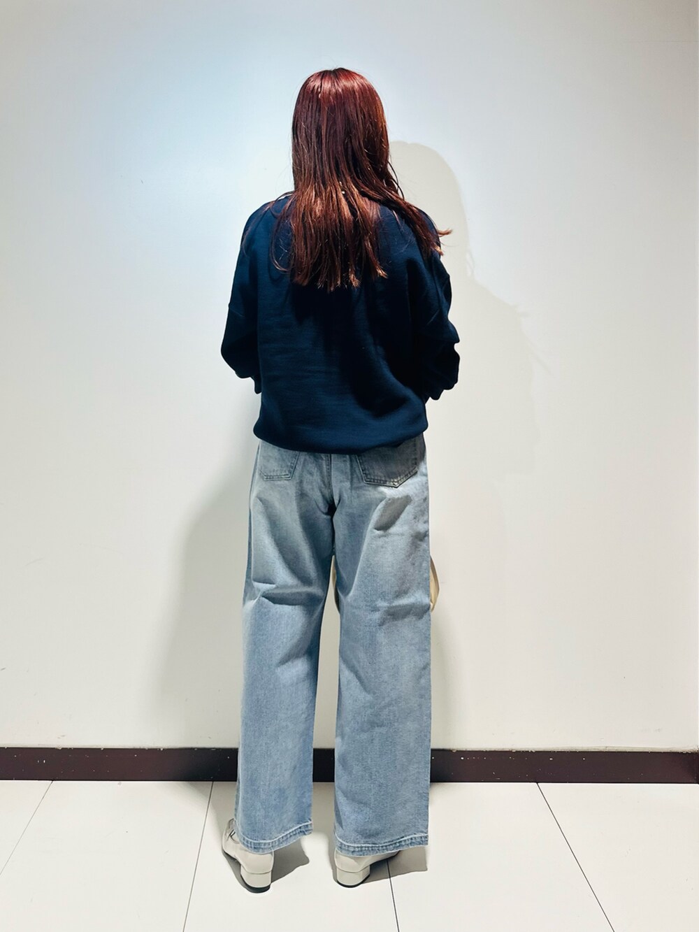 ブルー系のデニムパンツ、ブルー系のニット/セーター、ホワイト系のTシャツ/カットソーを着用したレディースの秋コーディネートの3枚目の写真