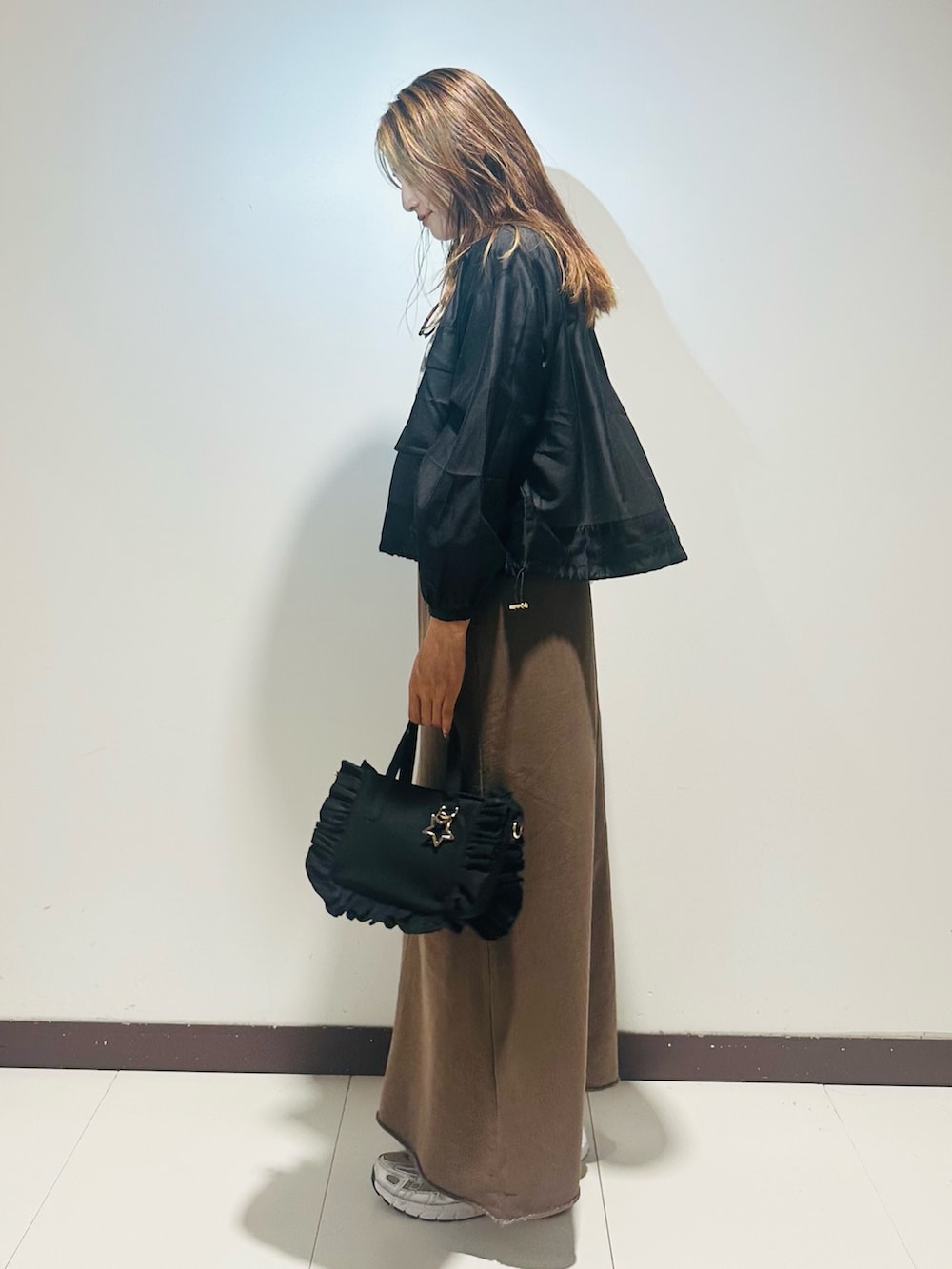 ブラック系のハンドバッグ、ブラウン系のスカート、ホワイト系のTシャツ/カットソーを着用したレディースの秋コーディネートの3枚目の写真