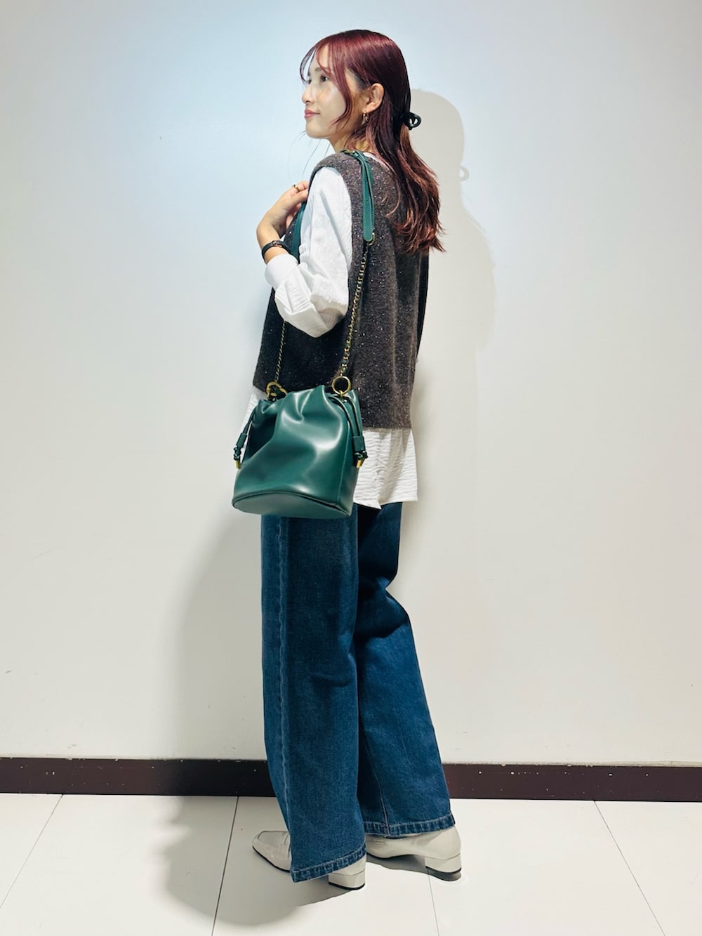 ブルー系のデニムパンツ、グリーン系のショルダーバッグ、ブラウン系のニット/セーターを着用したレディースの秋コーディネートの3枚目の写真