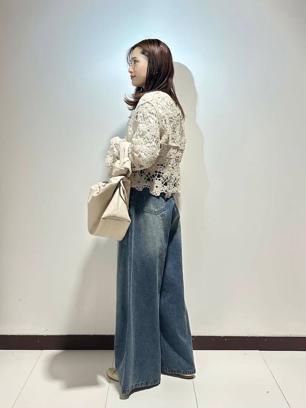 ホワイト系のハンドバッグ、ブルー系のデニムパンツ、ゴールド系のバレエシューズを着用したレディースの春コーディネートの2枚目の写真