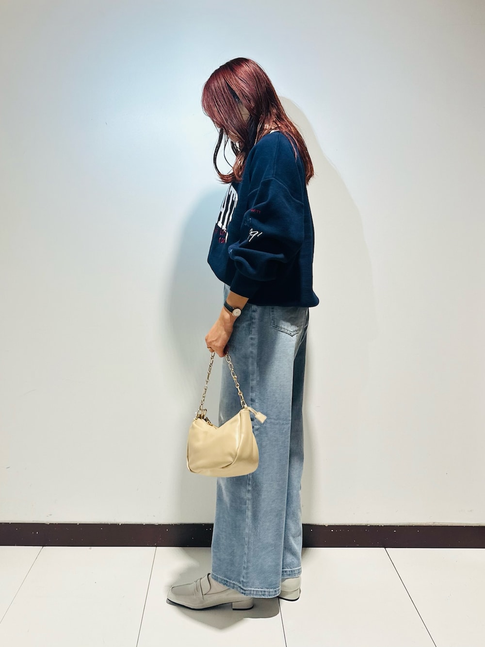 ブルー系のデニムパンツ、ブルー系のニット/セーター、ホワイト系のTシャツ/カットソーを着用したレディースの秋コーディネートの2枚目の写真