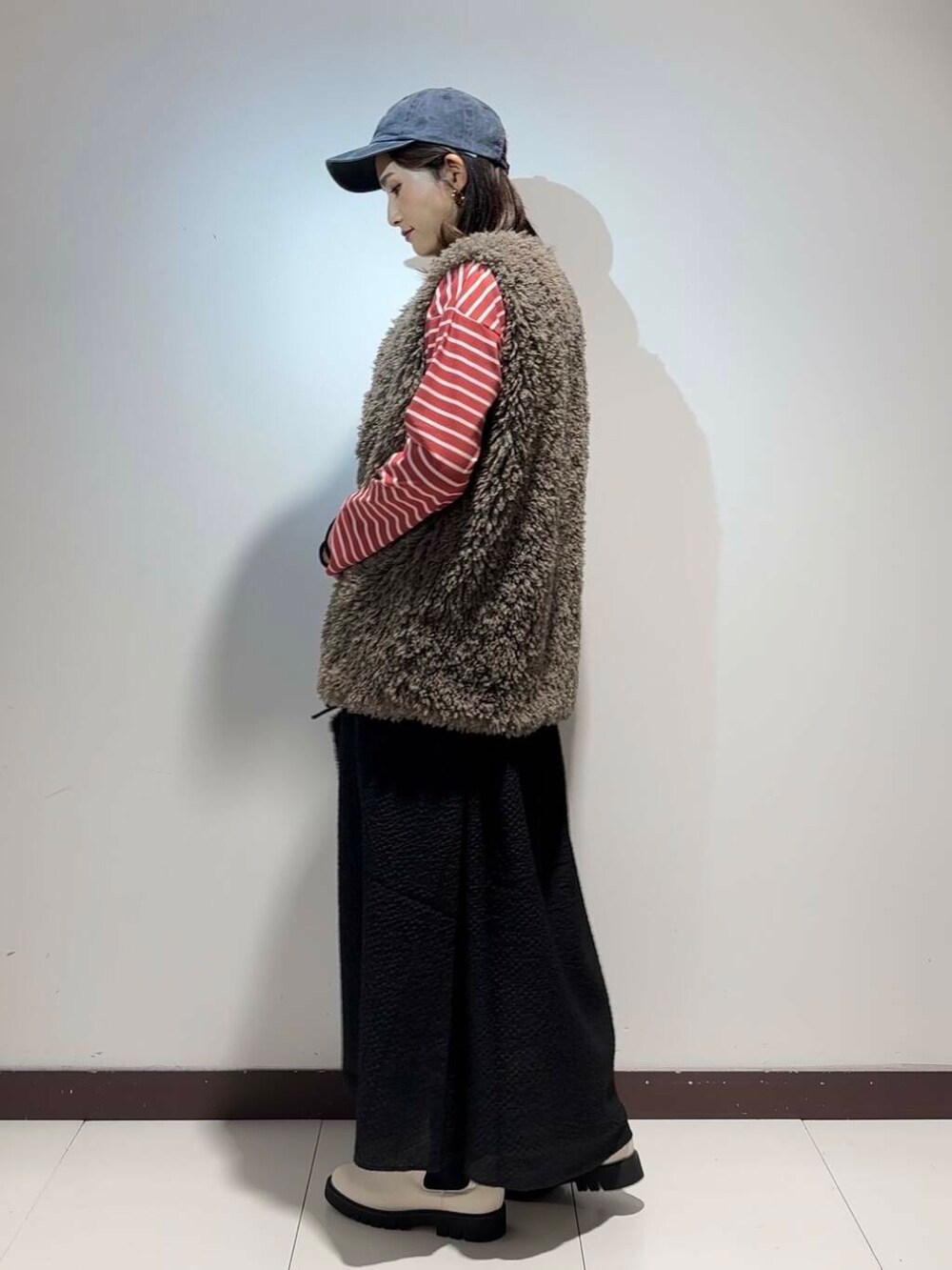 グレー系のベスト、ピンク系のTシャツ/カットソー、ブラック系のワンピースを着用したレディースの秋コーディネートの3枚目の写真