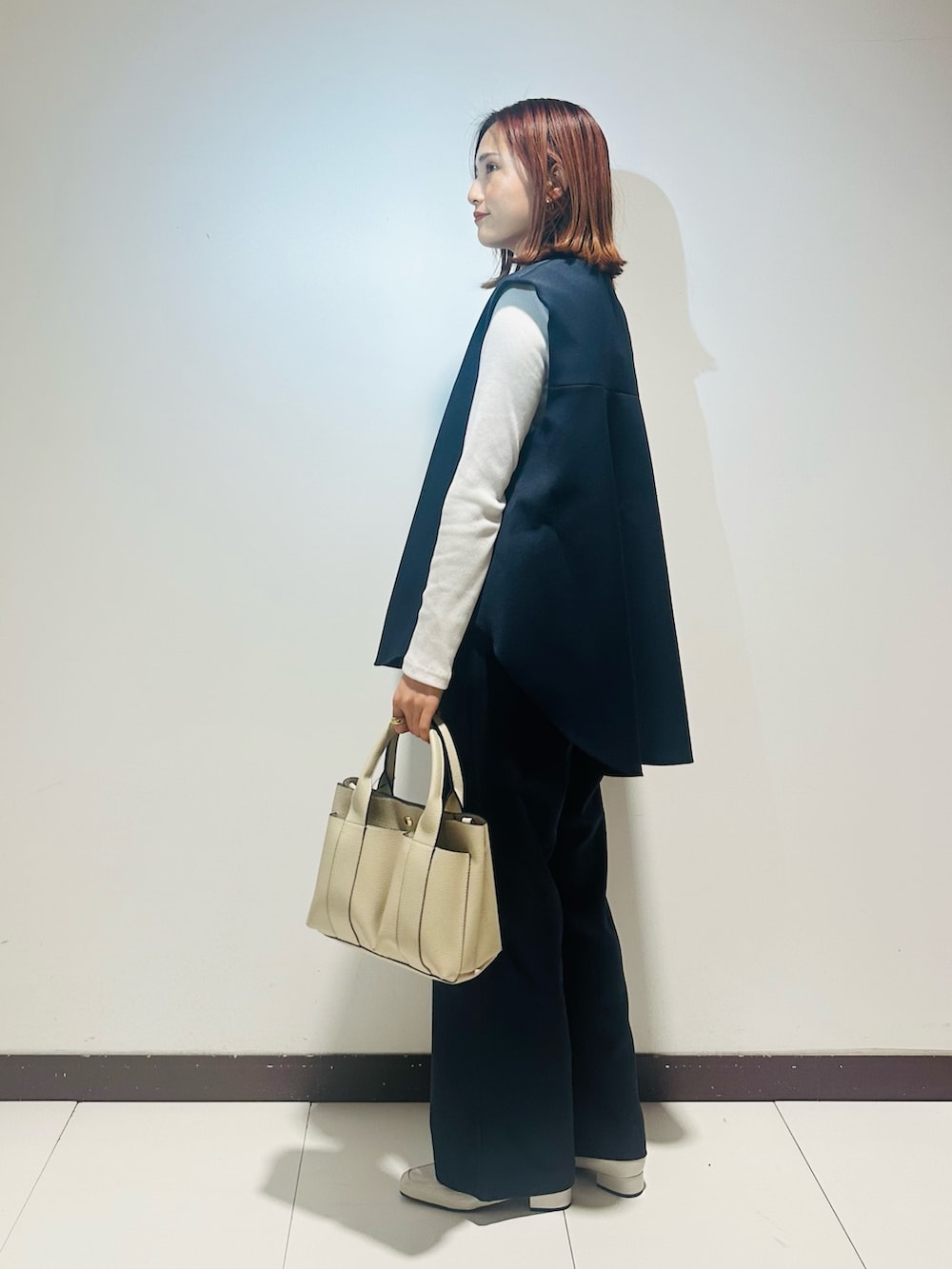 ホワイト系のトートバッグ、ブルー系のセットアップ、グレー系のローファーを着用したレディースの冬コーディネートの2枚目の写真