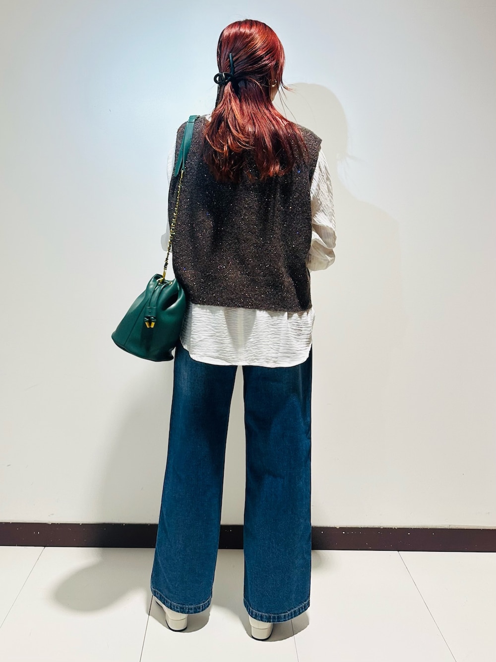 ブルー系のデニムパンツ、グリーン系のショルダーバッグ、ブラウン系のニット/セーターを着用したレディースの秋コーディネートの4枚目の写真