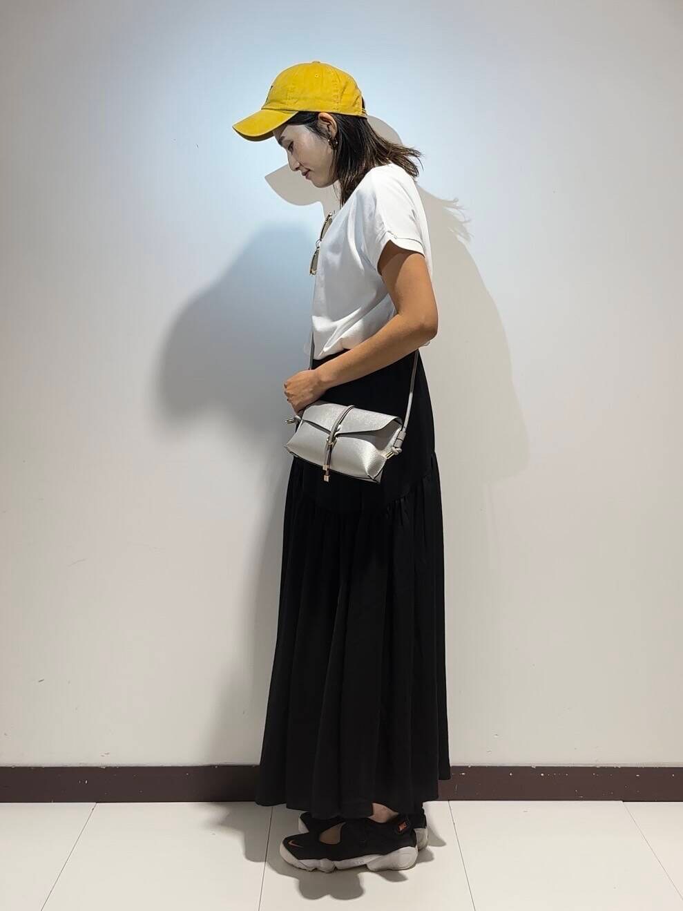 ホワイト系のワンピース、イエロー系のキャップを着用したレディースの夏コーディネートの2枚目の写真