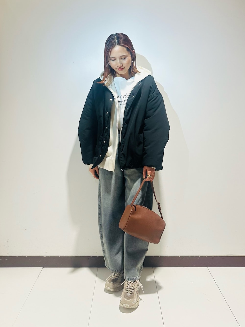 ブルー系のデニムパンツ、ブラック系のダウンジャケット/コート、ホワイト系のTシャツ/カットソーを着用したレディースの冬コーディネートの2枚目の写真