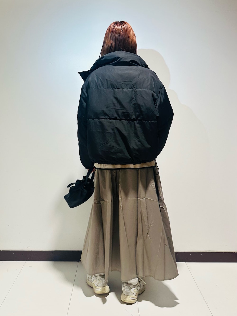 ブラック系のショルダーバッグ、ホワイト系のニット/セーター、グレー系のスカートを着用したレディースの秋コーディネートの4枚目の写真