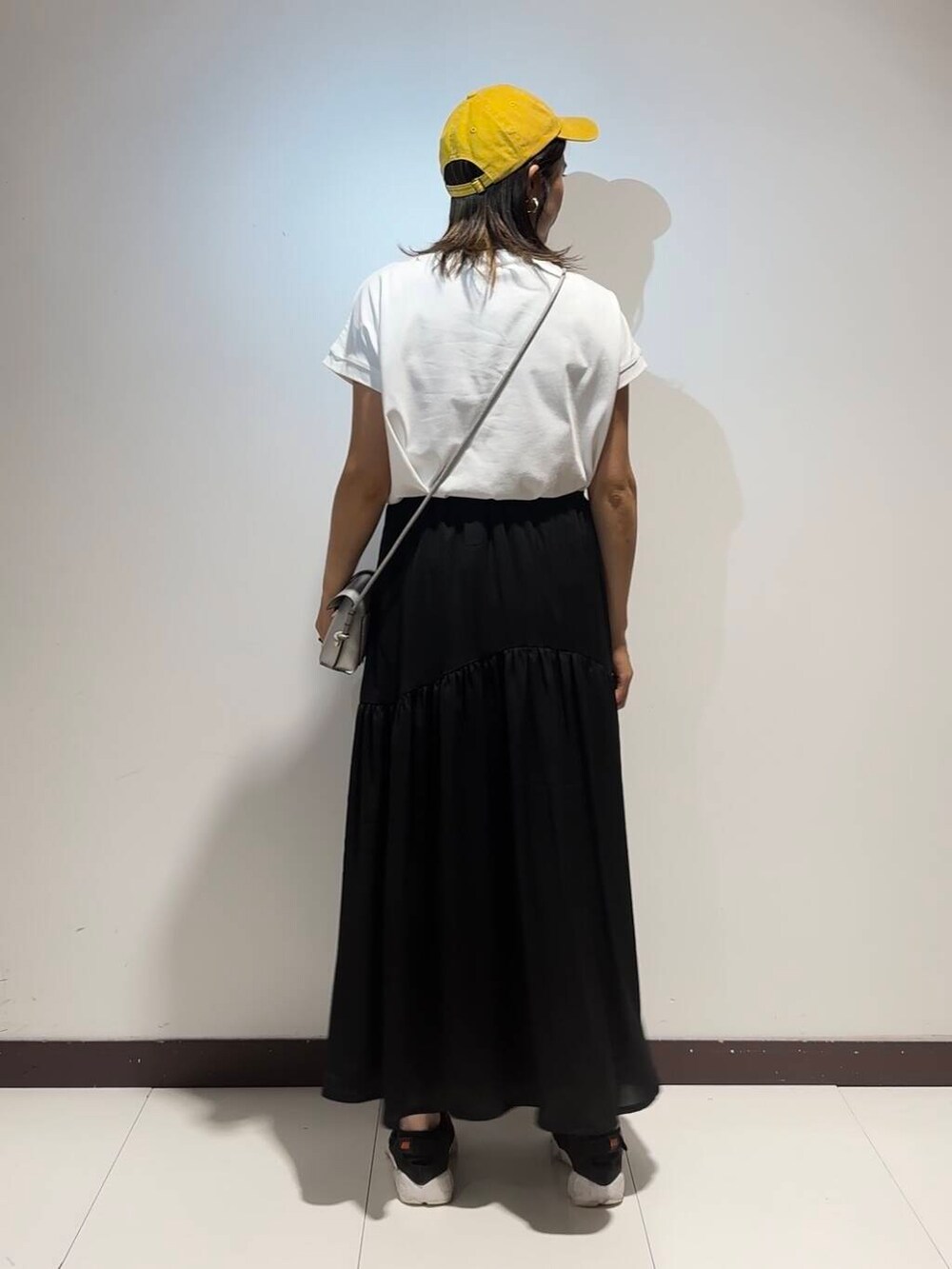 ホワイト系のワンピース、イエロー系のキャップを着用したレディースの夏コーディネートの3枚目の写真