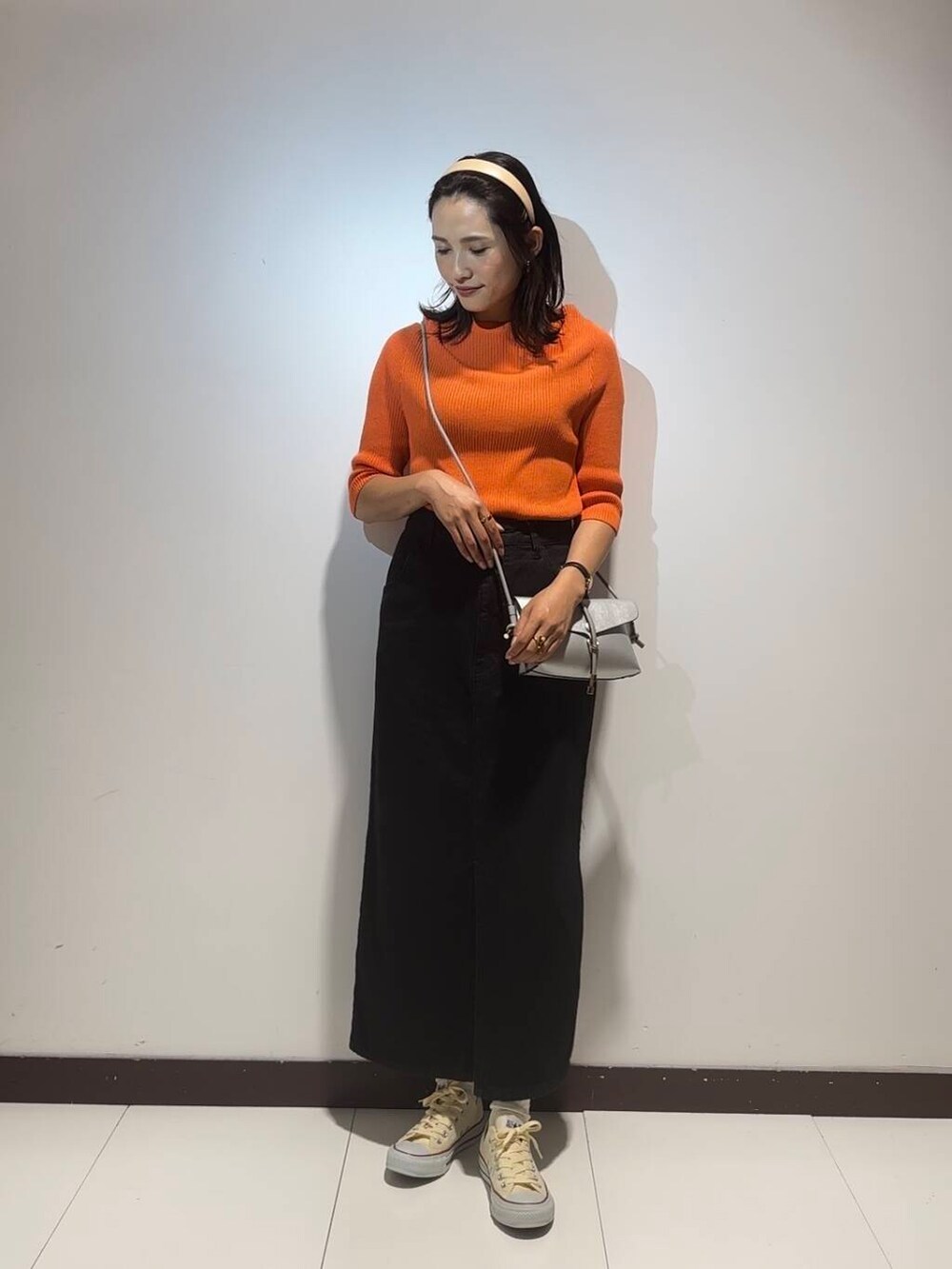 オレンジ系のニット/セーター、ブラック系のスカートを着用したレディースの夏コーディネートの2枚目の写真