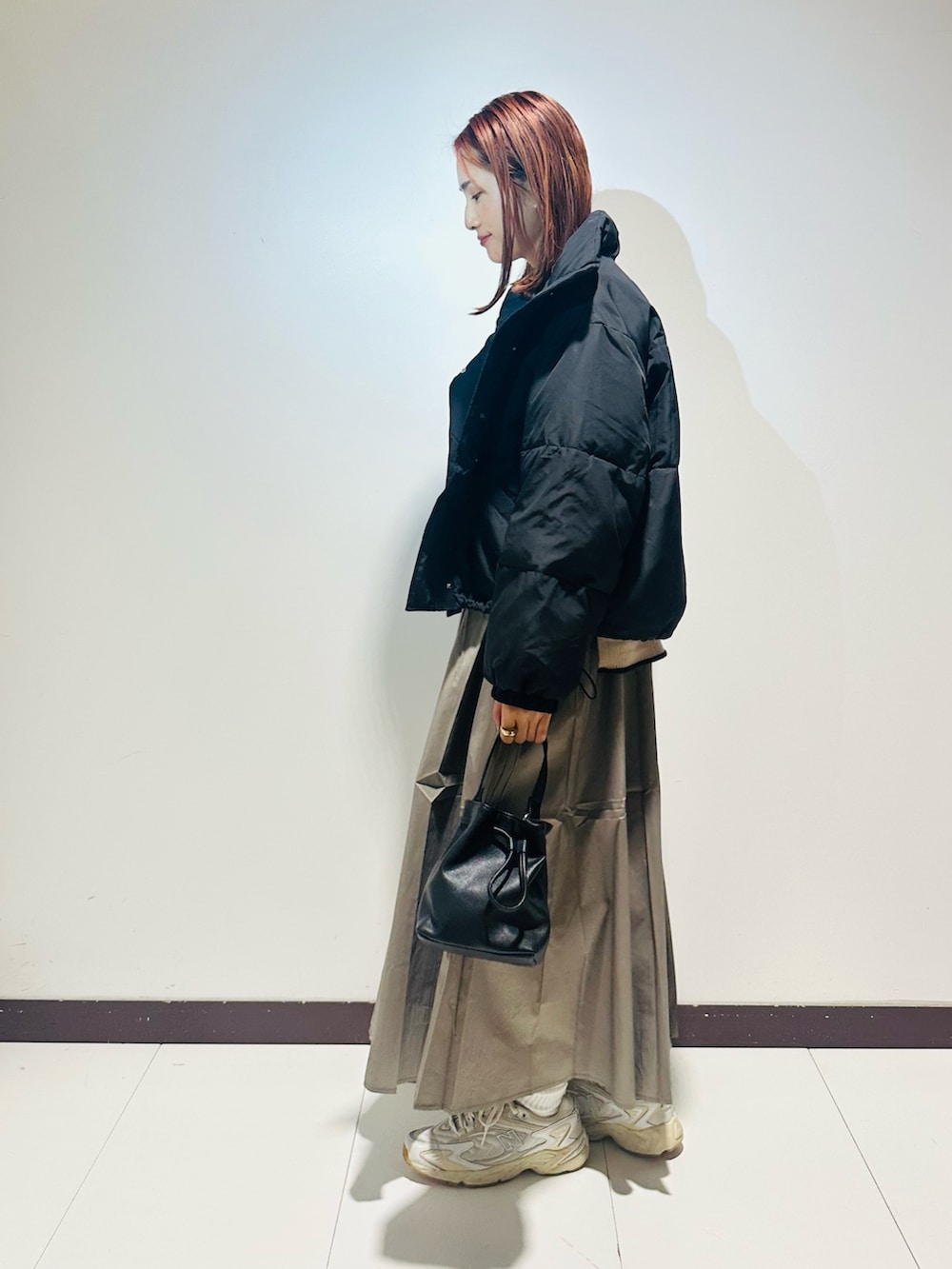 ブラック系のショルダーバッグ、ホワイト系のニット/セーター、グレー系のスカートを着用したレディースの秋コーディネートの3枚目の写真