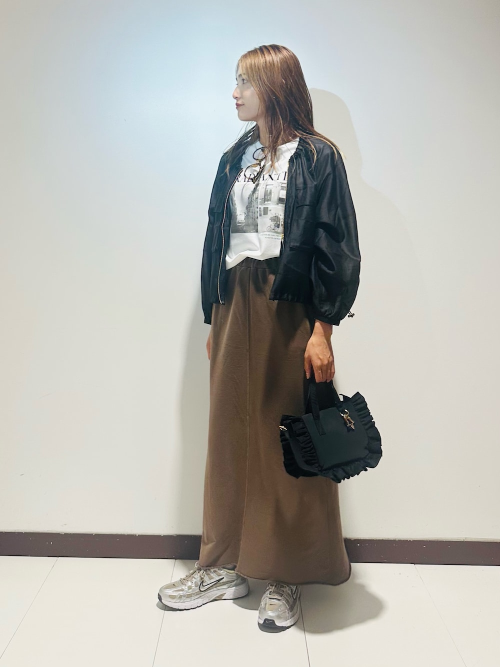 ブラック系のハンドバッグ、ブラウン系のスカート、ホワイト系のTシャツ/カットソーを着用したレディースの秋コーディネートの2枚目の写真