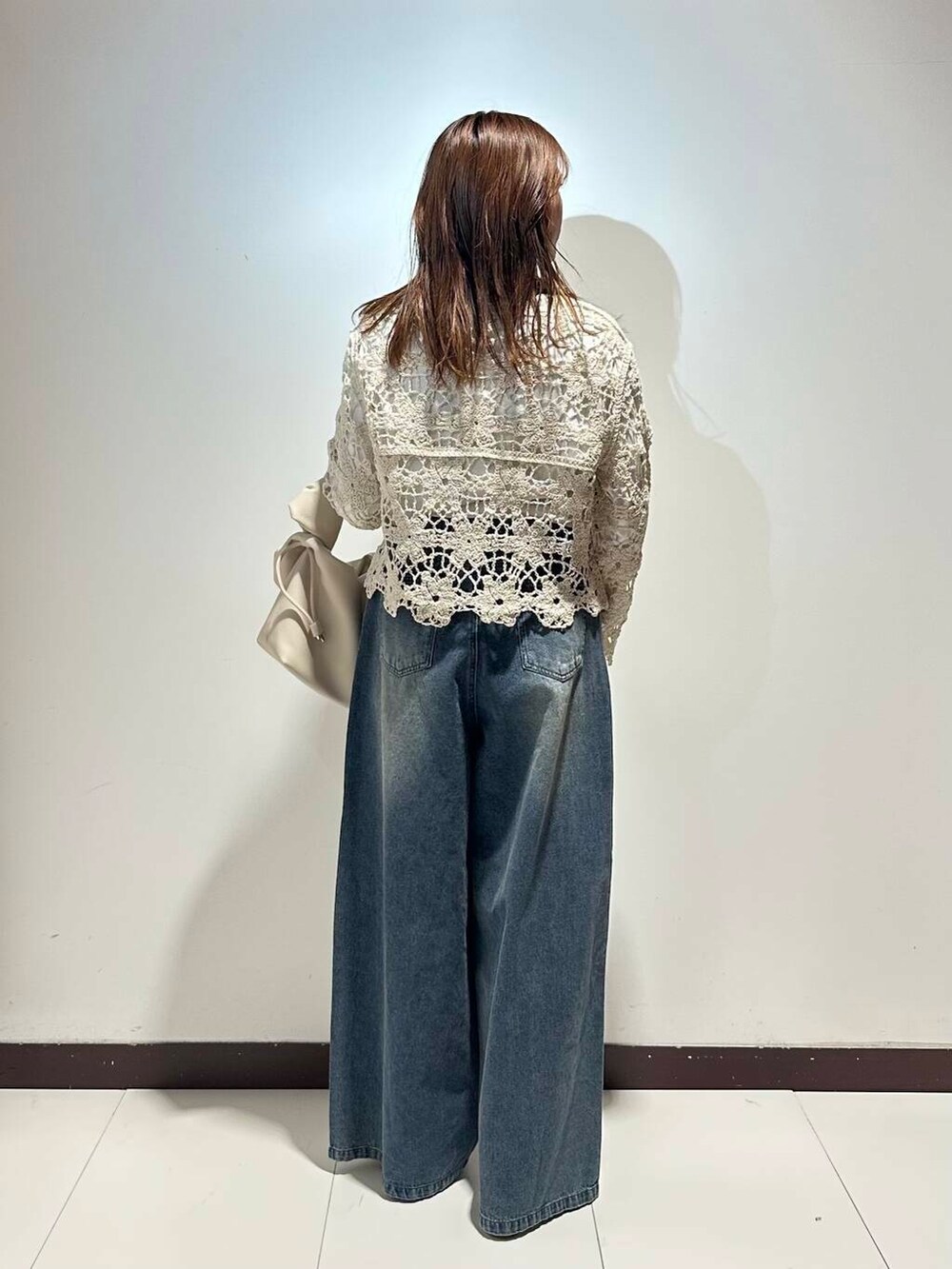 ホワイト系のハンドバッグ、ブルー系のデニムパンツ、ゴールド系のバレエシューズを着用したレディースの春コーディネートの3枚目の写真