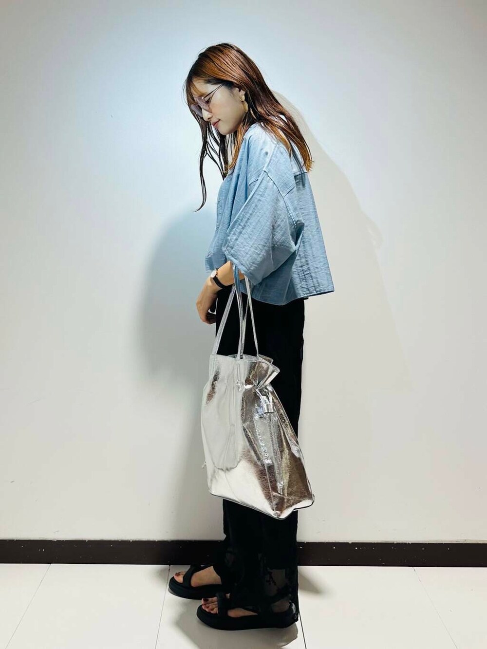 シルバー系のトートバッグ、ブラック系のその他パンツ、ホワイト系のタンクトップを着用したレディースの春コーディネートの3枚目の写真