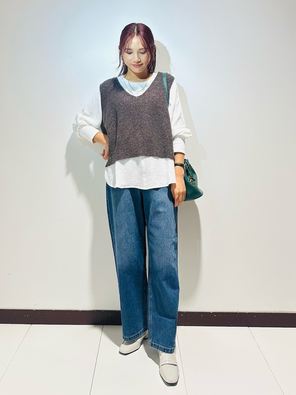 ブルー系のデニムパンツ、グリーン系のショルダーバッグ、ブラウン系のニット/セーターを着用したレディースの秋コーディネートの2枚目の写真