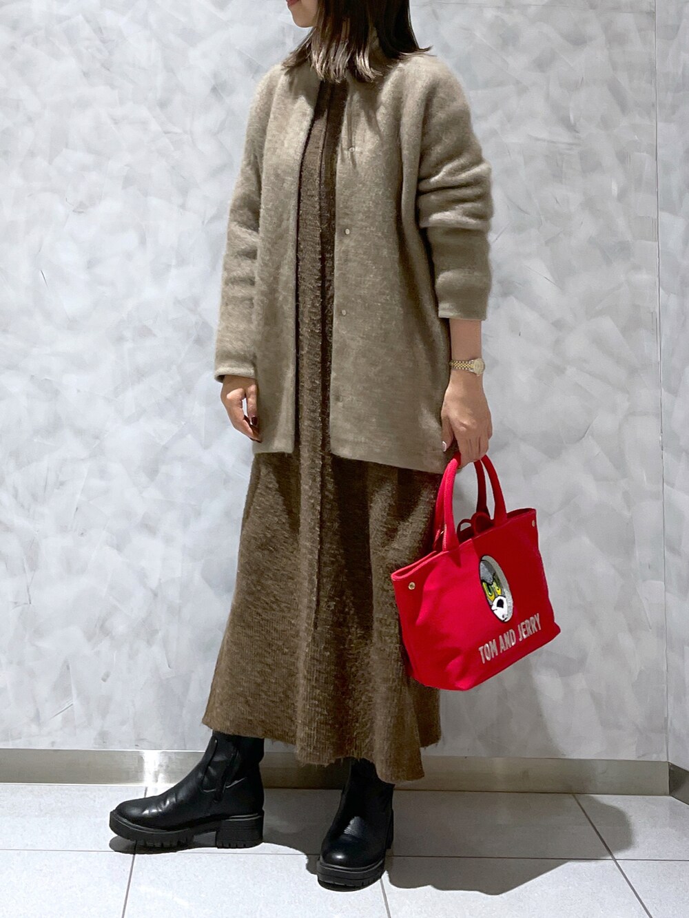 レッド系のトートバッグ、ブラウン系のワンピース、ブラック系のブーツを着用したレディースの冬コーディネートの2枚目の写真