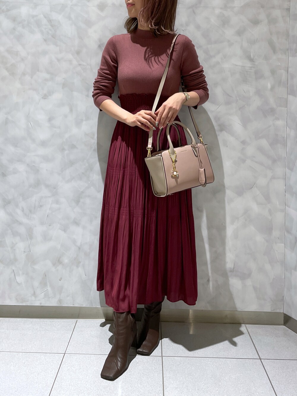 レッド系のワンピース、ブラウン系のブーツ、ピンク系のハンドバッグを着用したレディースの冬コーディネートの3枚目の写真