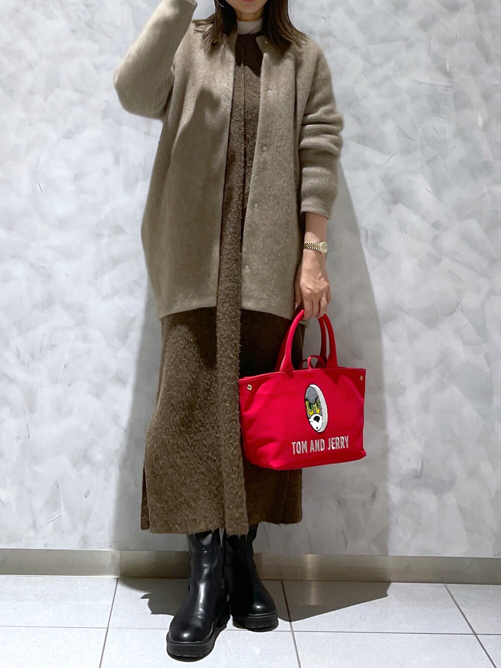 レッド系のトートバッグ、ブラウン系のワンピース、ブラック系のブーツを着用したレディースの冬コーディネートの3枚目の写真