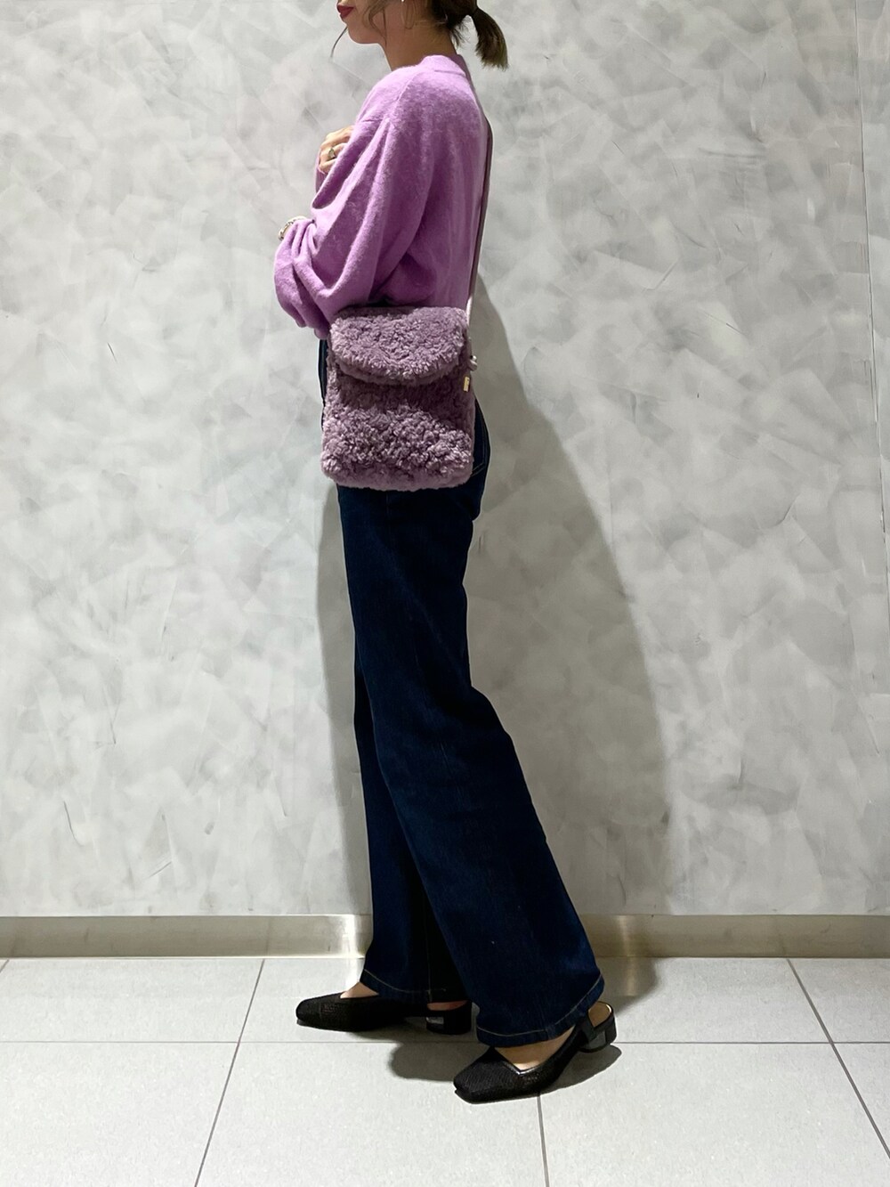 ブルー系のデニムパンツ、ブラック系のパンプス、パープル系のショルダーバッグを着用したレディースの秋コーディネートの4枚目の写真