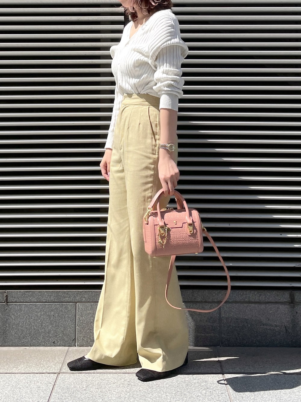 イエロー系のパンツ、ピンク系のショルダーバッグ、シルバー系のトップスを着用したレディースの春コーディネートの4枚目の写真