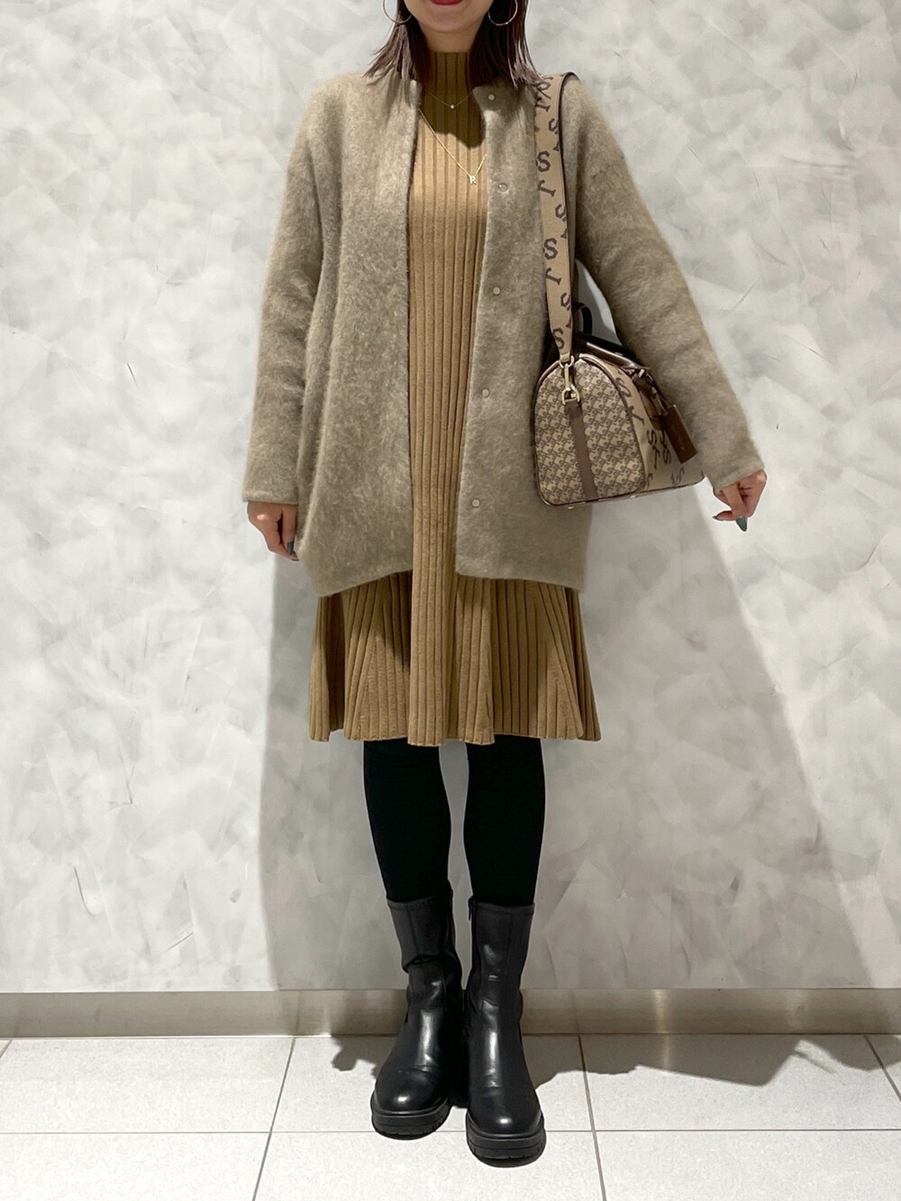 ブラウン系のボストンバッグ、ブラウン系のワンピース/ドレス、ベージュ系のカーディガン/ボレロを着用したレディースの冬コーディネートの2枚目の写真