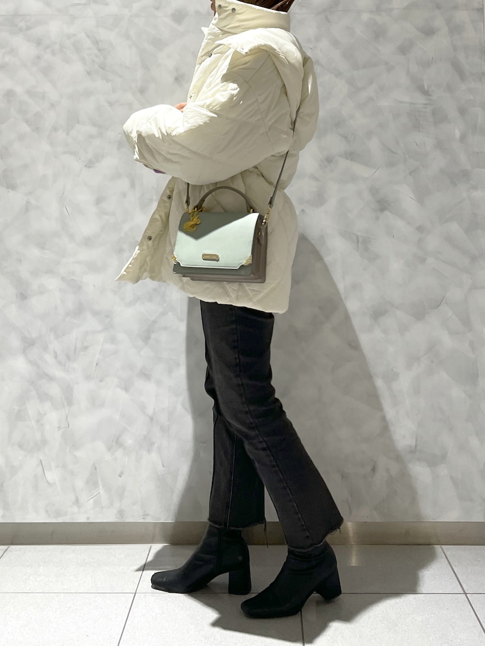 ホワイト系のその他アウター、グリーン系のショルダーバッグを着用したレディースの冬コーディネートの2枚目の写真