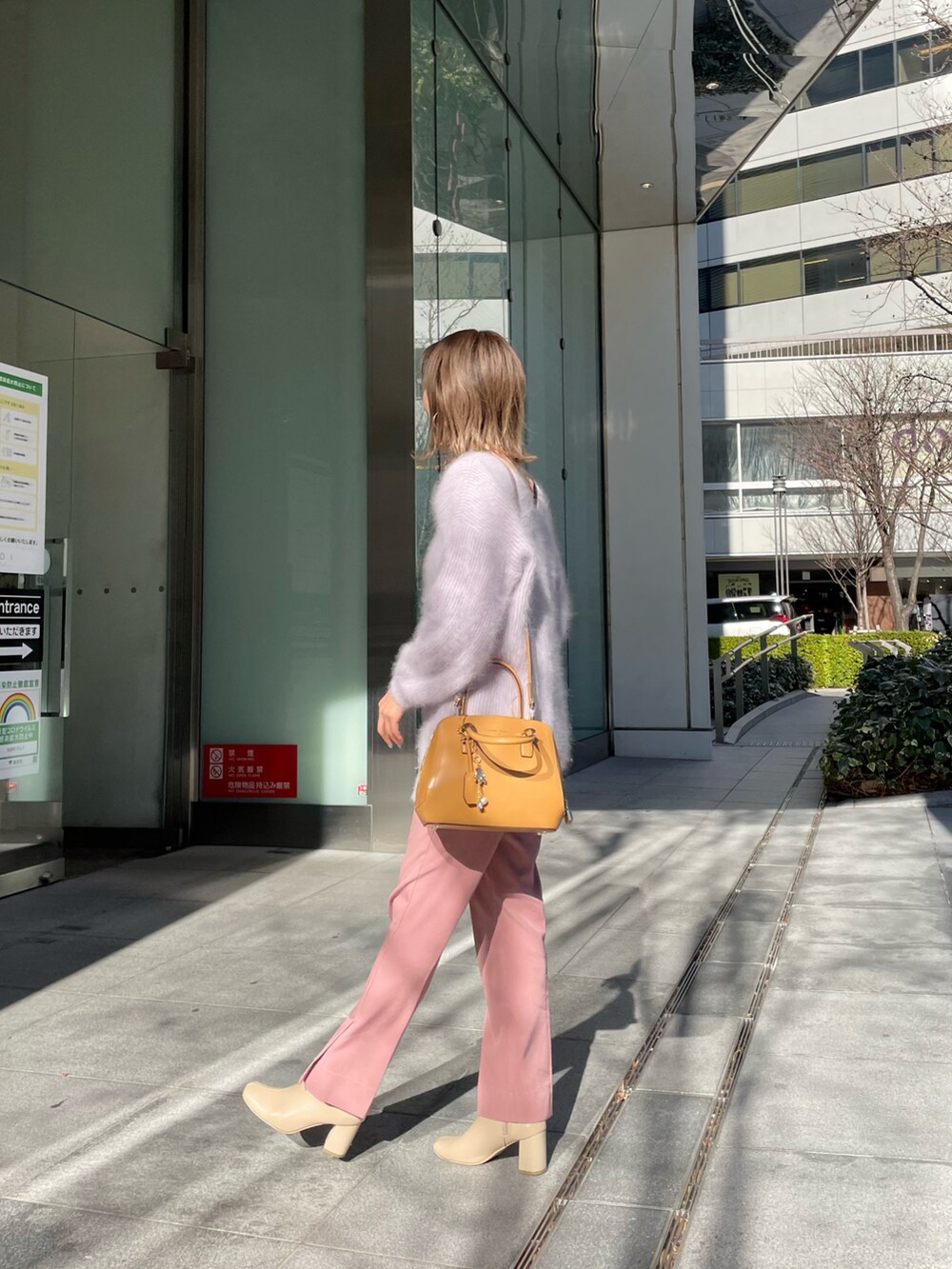 イエロー系のハンドバッグ、パープル系のニット/セーターを着用したレディースの冬コーディネートの3枚目の写真