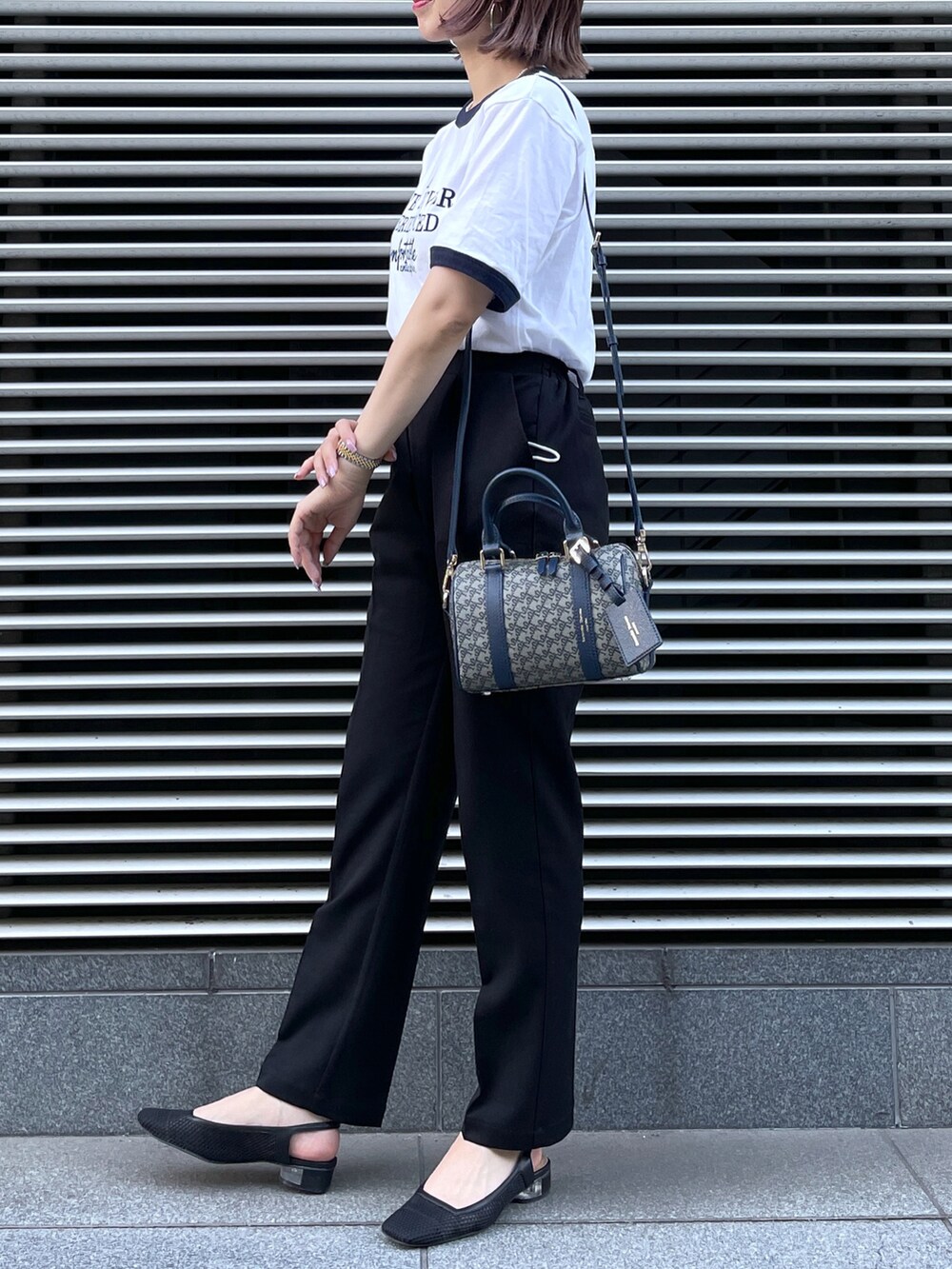 ブルー系のショルダーバッグ、ブラック系のスラックス、ブルー系のTシャツ/カットソーを着用したレディースの春コーディネートの2枚目の写真