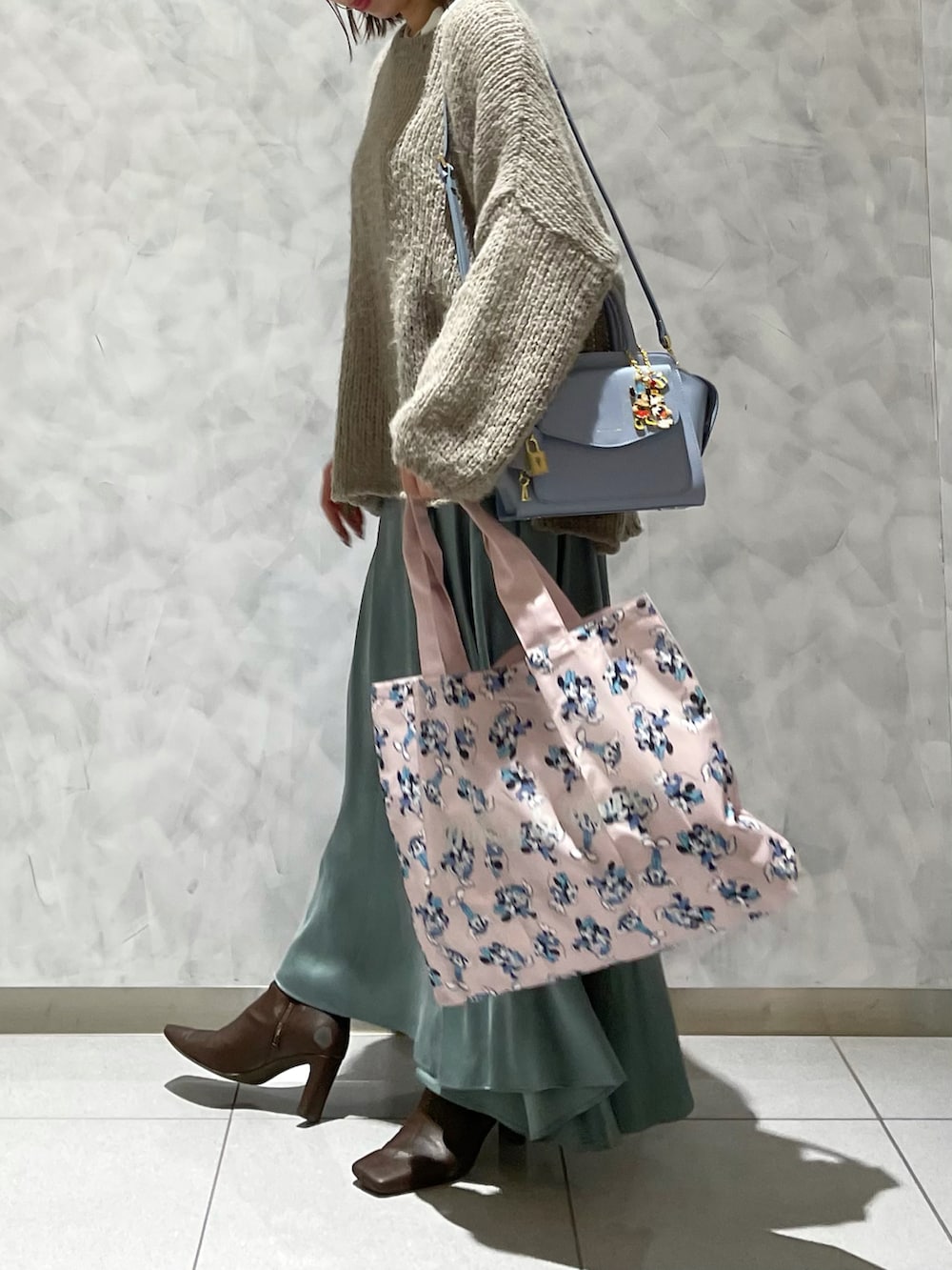 ピンク系のハンドバッグ、ブルー系のハンドバッグ、グリーン系のスカートを着用したレディースの秋コーディネートの2枚目の写真