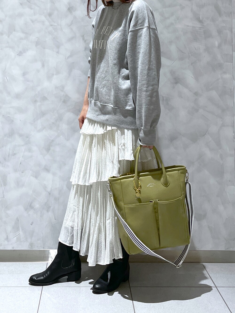 グリーン系のトートバッグ、グレー系のスウェットを着用したレディースの春コーディネートの3枚目の写真