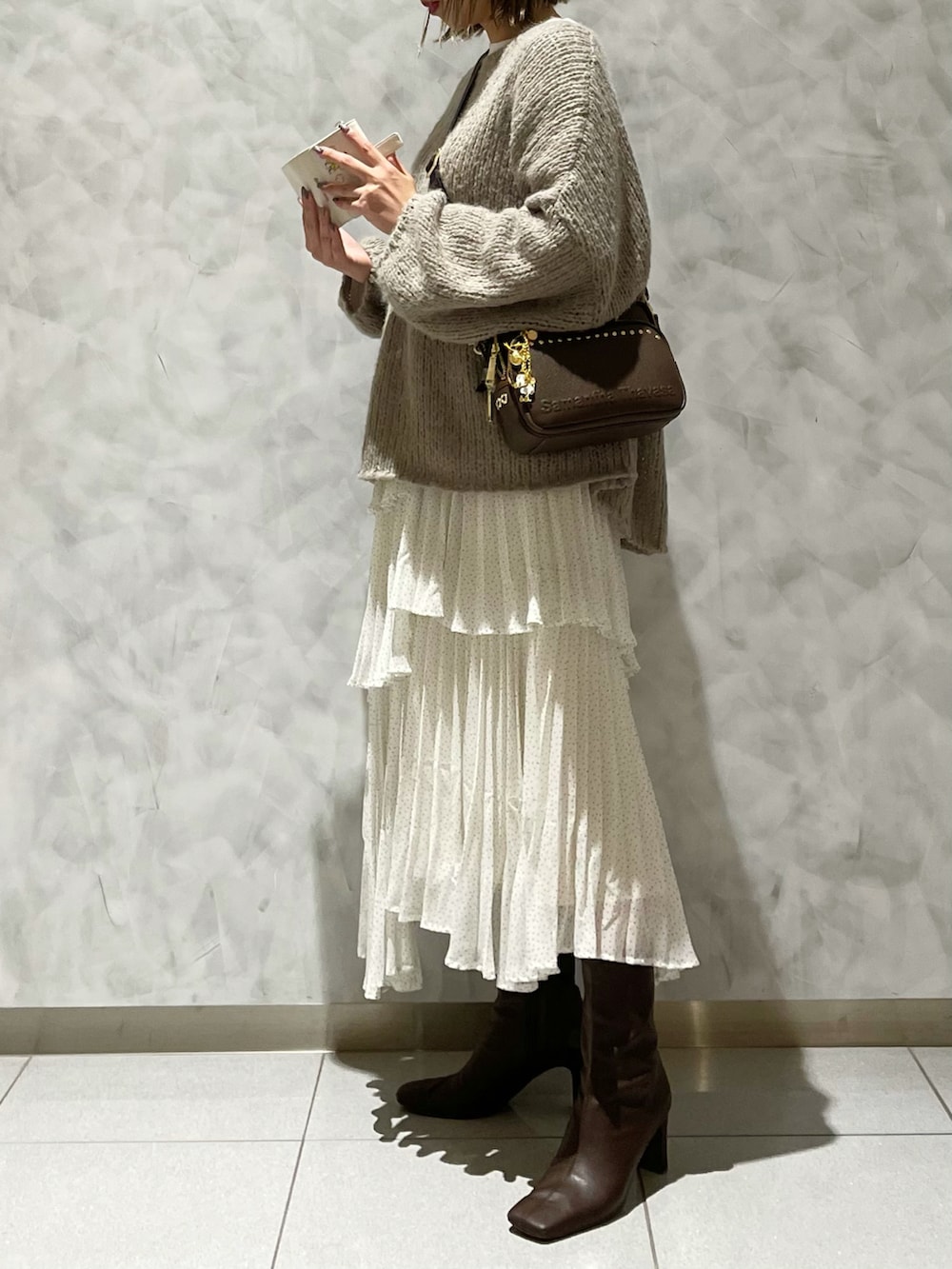 ブラウン系のブーツ、ホワイト系のスカート、ベージュ系のニット/セーターを着用したレディースの冬コーディネートの3枚目の写真