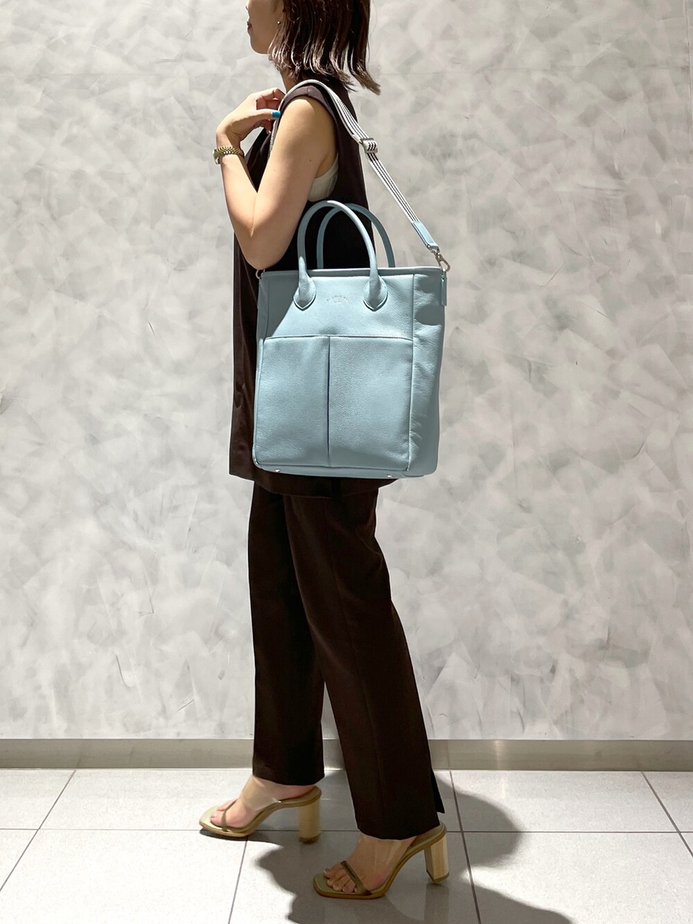 ブルー系のトートバッグ、グリーン系のサンダルを着用したレディースの夏コーディネートの4枚目の写真