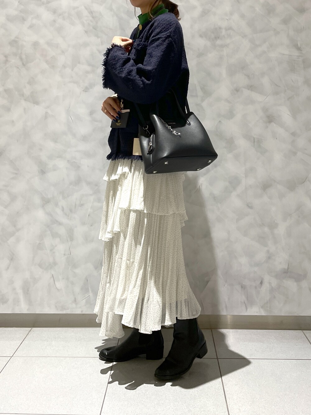 ホワイト系のスカート、ブルー系のジャケット/アウター、ブラック系のハンドバッグを着用したレディースの春コーディネートの2枚目の写真