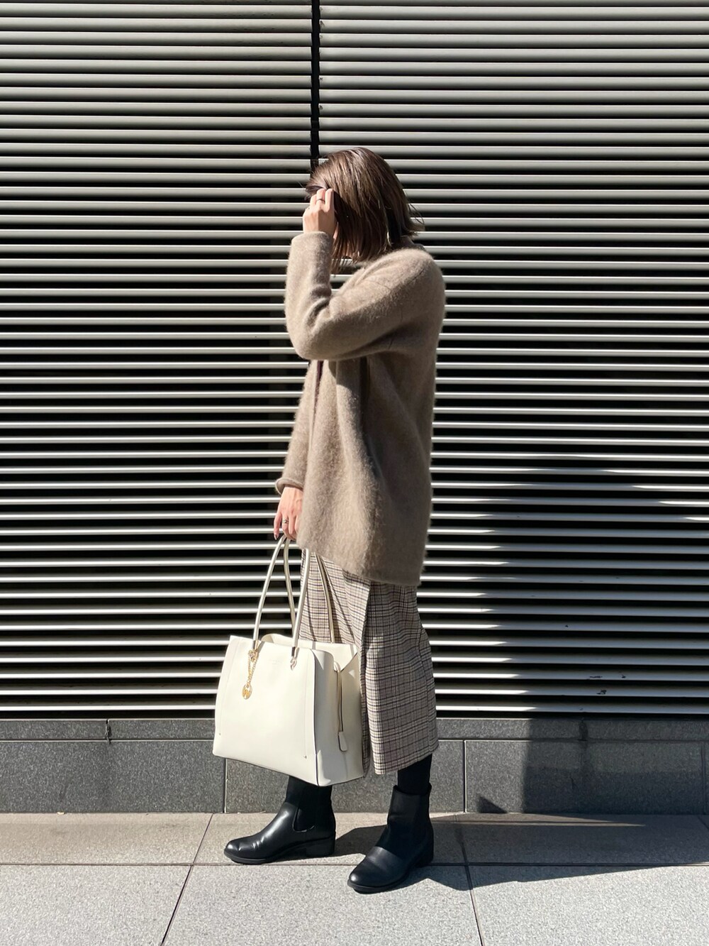 ホワイト系のトートバッグ、ベージュ系のカーディガン/ボレロ、ベージュ系のニット/セーターを着用したレディースの冬コーディネートの3枚目の写真