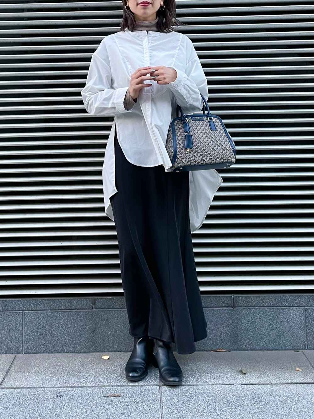 ブラウン系のハンドバッグ、ホワイト系のシャツ/ブラウス、ブラック系のスカートを着用したレディースの冬コーディネートの3枚目の写真