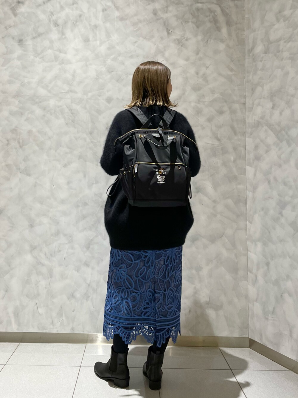 ブルー系のスカート、ブラック系のカーディガン/ボレロ、ブラック系のバックパック/リュックを着用したレディースの冬コーディネートの3枚目の写真