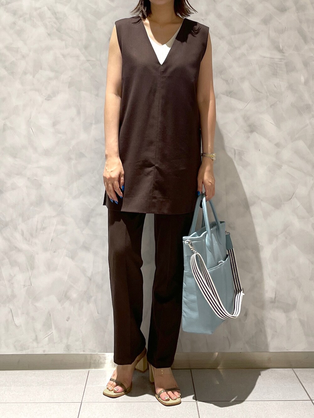 ブルー系のトートバッグ、グリーン系のサンダルを着用したレディースの夏コーディネートの2枚目の写真