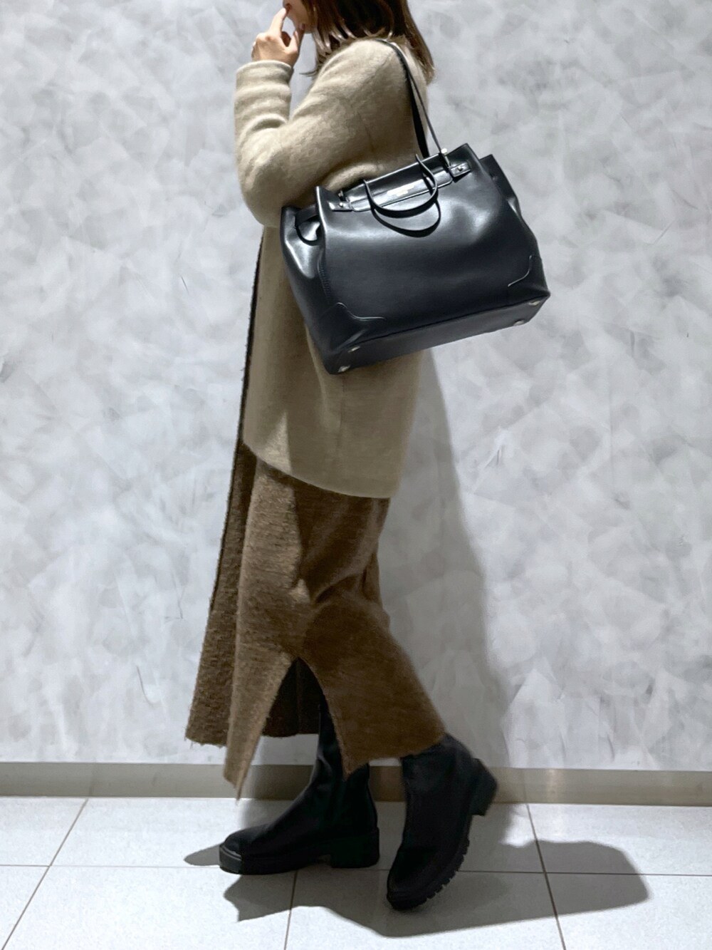ブラック系のトートバッグ、ブラウン系のワンピース、ベージュ系のカーディガン/ボレロを着用したレディースの冬コーディネートの3枚目の写真